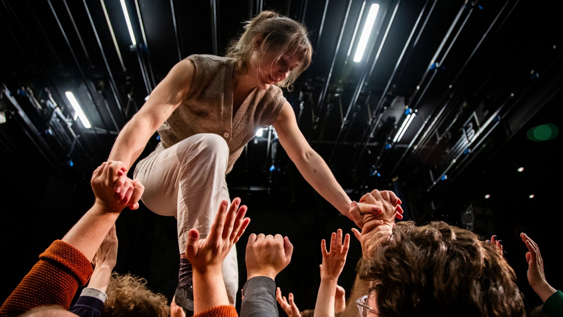 Een circusartiest balanceert op de handen van meerdere personen