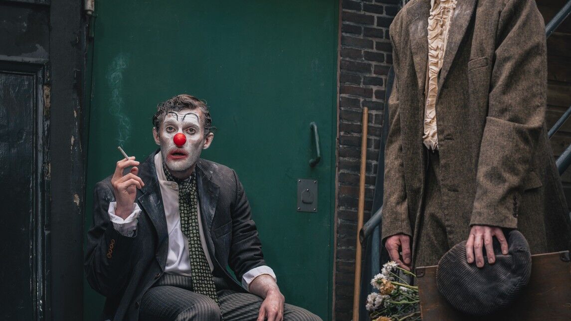 Een clown met een rode neus rookt een sigaret