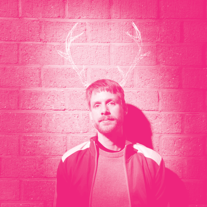 Man staat tegen een muur aan met rendier horens op de muur getekend met een roze filter